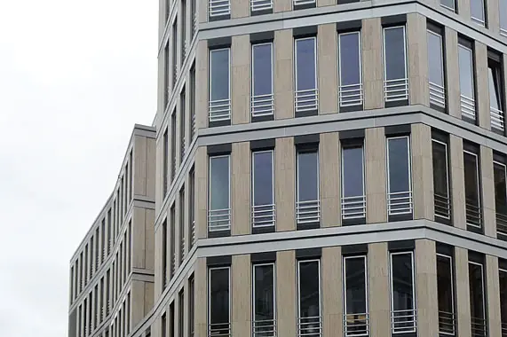 Natursteinfassade mit durchlaufenden Fensterbändern – Montage durch Reiss Metallbau